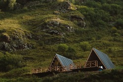 Cute triangle houses on a background of green grass of high mountains. 