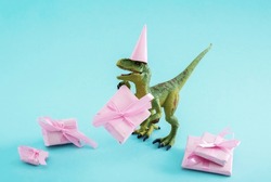 Cute green dinosaur with gift box and party hat on a blue background. Cute minimal birthday concept.