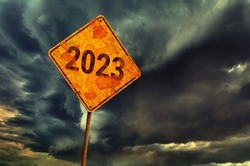 Dark dramatic sky with thunderclouds and old yellow rhombic road sign with number 2023