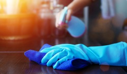 hand in blue rubber glove holding blue microfiber cleaning cloth and spray bottle with sterilizing solution make clean and disinfection for good hygiene