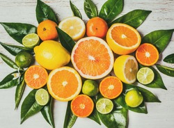 Citrus background. Assorted fresh citrus fruits with leaves. Lemon, orange lime, grapefruit mandarin. Harvest concept. Top view. White wooden background.