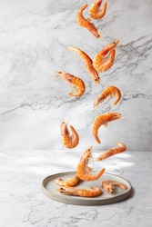 Flying food. Seafood shrimps prawns fly over gray plate, Marbled background.