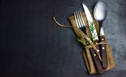 Rustic vintage set of cutlery knife, spoon, fork. Black background. Top view