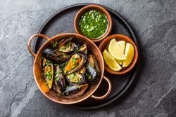 Shellfish Mussels in copper bowl with lemon and herbs sauce. Top view.