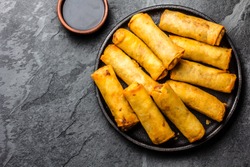 Fried spring rolls on black iron plate on grey stone slate background. Top view, copy space