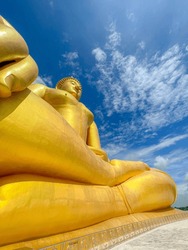 Full body old Buddha statue with raw of Brass. Two Hand of buddha statue with stamp on chest with the fresh sky background. Believe, Culture, Traditional. Concept of Buddhist believe and merit.
