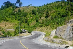 Southern Cross Route (JLS) Tulungagung-Trenggalek, East Java, Indonesia. Winding asphalt road with yellow lines, on the side of steep rock cliffs during the day