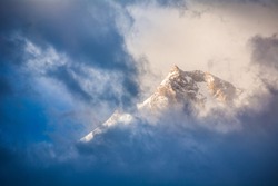 Golden sunrise behind dark blue clouds passing over the peak of Nanga Parbat mountain in the Himalayas in northern Pakistan