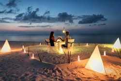Honeymoon couple is having a private, romantic dinner at a tropical beach