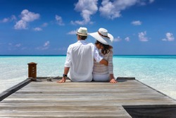 Elegant honeymoon traveler couple hugging on a wooden jetty and enjoy their tropical holiday in the Maldives islands