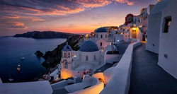 Beautiful view to the three blue domed churches in the village of Oia, Santorini, Greece, during dusk without people