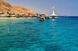 View on coral beach and bungalows for divers and vacationers, marine nature museum and pleasure boat, the area located near coral reefs in Eilat - famous tourist resort city in Israel, Middle East