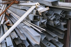 Stacks of metal profile channel piled up at a construction site in the form of scrap metal