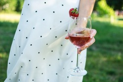 A glass of wine rose in the hand of a girl at the party. Summer holiday, birthday, anniversary, wedding outdoor.