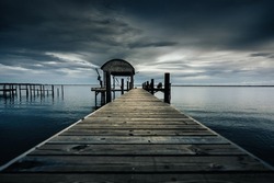 Dark ocean dock on gloomy day with moody vibes. Calm before the storm. Choctawhatchee Bay Freeport, Florida.