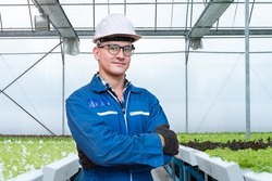 workers engineering standing with confident with working suite dress and safety helmet in front of greenhouse. worker constructs a system hydroponics for agriculture plants and vegetable.