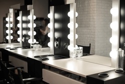 Blurred background of a beauty salon, a make-up table with lighting, cinema lights, interior of a hairdressing salon