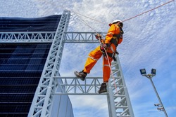 worker on high wear dresses and safety man with harness concept on steel structures success from work in site construction on blue sky background