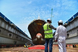 Engineering Shipyard working in dry dock yard The bulk carrier general cargo ship in dry dock yard, recondition of hull repairing and repainting,  