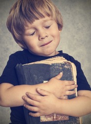 Little boy hugging an old book, he is happy