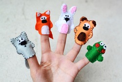 Hand wearing 5 finger puppets; wolf, fox, rabbit, bear, frog