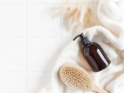 Brown bottle mockup for bathing products in bathroom, spa shampoo, shower gel, liquid soap on cotton towel and wood brush flat lay. Top view. copy space