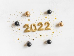 Greeting card - happy new year with numbers 2022, gold glitter and christmas balls on white textured background. Minimal holiday concept. Top view. Flat lay