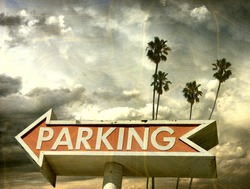 aged and worn vintage photo of parking sign with palm trees