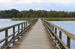 Wooden bridge for pedestrians on Sirvenos Lake, Birzai, Lithuania. Evening in very early autumn.