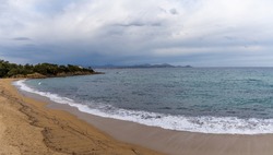 Empty peaceful golden sand beach on the French Riviera under an expressive overcast sky
