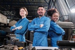Multiracial industry workers in safety uniforms collaborate with unity, arms crossed, and express happy work together with smile and cheerful in mechanical factory, professional engineer occupation.