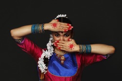 A girl is dancing an Indian dance. A dancer dances in a studio on a black background.