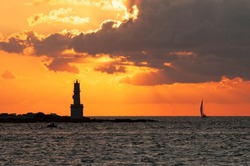 View of the island of Formentera harbor and its lighthouse at sunset with sailboats sailing by. Travel and tourism concept