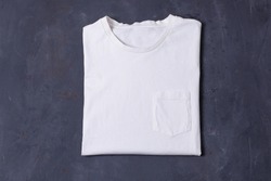 Basic white Tshirt on grey concrete background. Mock up for branding t-shirt with pocket. 