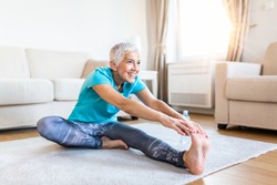 senior woman doing warmup workout at home. Fitness woman doing stretch exercise stretching her legs,quadriceps .Elderly woman living an active lifestyle.