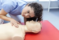 woman practicing cpr technique on dummy during first aid training. First Aid Training - Cardiopulmonary resuscitation. First aid course on cpr dummy.