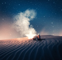 Young girl sitting next to a fallen star in the desert.