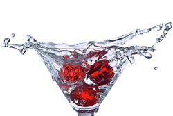 Red Dice falling in the martini glass with splashes of water isolated on white