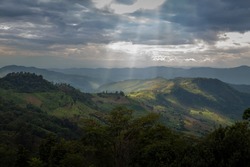 Sunbeam over the valley. Light rays from clouds shining down on mountains. Sun rays over hill. Beams of light from clouds on the mountains. Majestic nature. Doi Chang, Chiang Rai, Thailand 