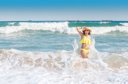 Young woman tourist in swimsuit having fun in wavy waters of Mediterranean sea, storm weather at the sea concept
