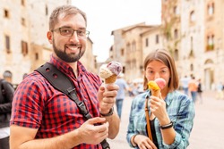 Happy group of friends eating ice-cream in old town center in Italy, travel and food concept