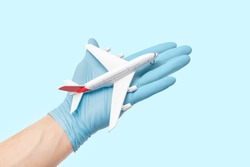 Doctor in medical gloves is holding a toy airplane. Concept of flight restriction and quarantine. Humanitarian assistance and emergency situation