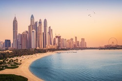 Sunset view of the Dubai Marina and JBR area and the famous Ferris Wheel and golden sand beaches in the Persian Gulf. Holidays and vacations in the UAE