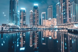 Hotels and apartment residential skyscraper buildings panoramic view in Dubai Marina Creek Harbour at night with reflections in water