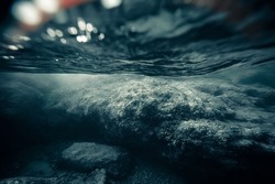 A deserted and dark mystical underwater landscape with large rocks in shallow sea coast. Narrow depth and soft focus. Gloomy and moody atmosphere