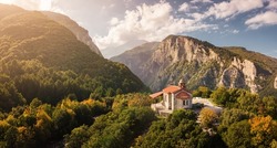 Aerial drone panoramic view of a little church on a cliff in deep canyon near legendary Mountain Olympus - the pantheon of all Greek gods and Great Zeus. National Parks in Greece