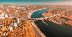 Aerial cityscape view of city districts with automobile bridge over river in Ufa. Autumn parks with colorful trees