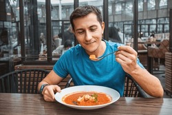 Man eating delicious tomato soup in cafe or restaurant. Vegetarian cuisine and healthy vegetable diet. Dinner and meal with organic products