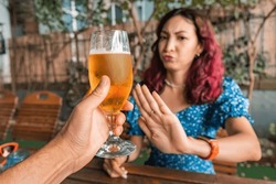 Funny drunk woman refuses an extra glass of beer at the bar. Say no and stop to addiction and excessive alcohol consumption.