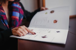 close up of woman finger with menu choosing dishes at restaurant